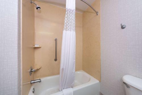 a bathroom with a shower with a white shower curtain at Hampton Inn Kansas City Northeast in Kansas City