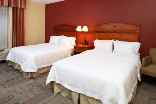 a hotel room with two beds and a chair at Hampton Inn Kansas City Northeast in Kansas City