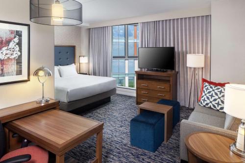 ボストンにあるHomewood Suites by Hilton Boston Seaport Districtのベッドとテレビ付きのホテルルーム