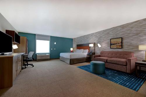 a hotel room with a bed and a couch and a tv at Home2 Suites By Hilton Barstow, Ca in Barstow