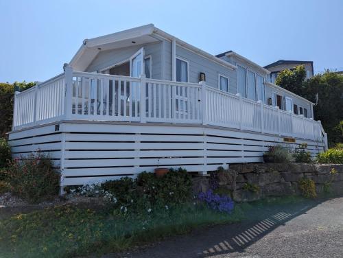 Caravan Swanage Bay View Holiday Park Dorset Amazing Location في سواناج: منزل أبيض كبير مع شرفة كبيرة