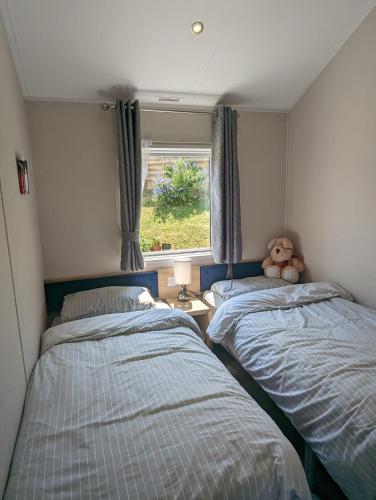 two beds in a room with a teddy bear sitting between them at Caravan Swanage Bay View Holiday Park Dorset Amazing Location in Swanage
