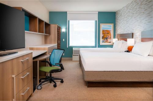 a hotel room with a bed and a desk and a tv at Home2 Suites Corona, Ca in Corona