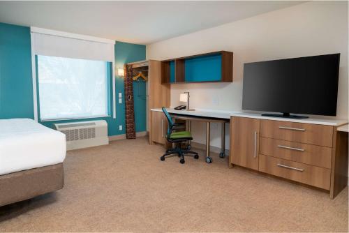 a hotel room with a desk and a television at Home2 Suites Corona, Ca in Corona