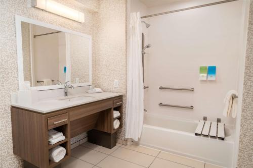 a bathroom with a sink and a tub and a mirror at Home2 Suites Corona, Ca in Corona