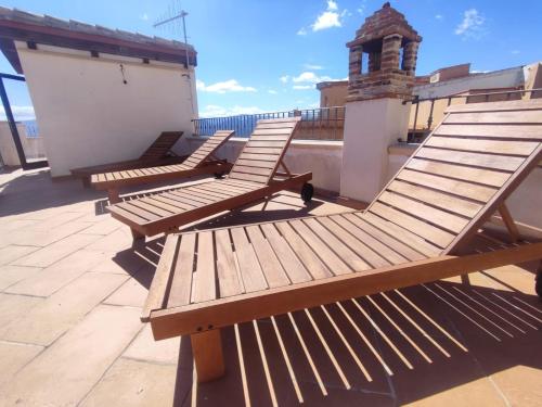 three wooden benches sitting on top of a roof at La Casa delle Rondini in Baunei