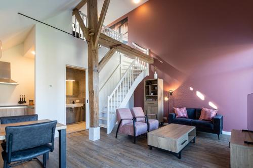 a living room with furniture and a staircase at Boerderijkamer de Hooizolder in Wijhe