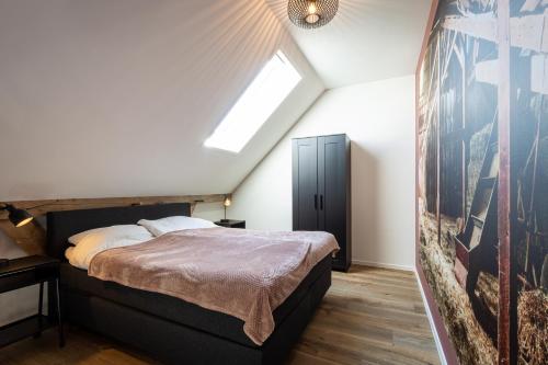 een slaapkamer op zolder met een bed en een dakraam bij Boerderijkamer de Hooizolder in Wijhe