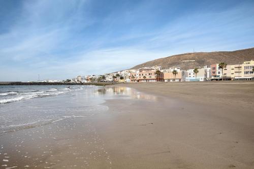 a sandy beach with buildings and the ocean at Apartamento Las Palmeras in Gran Tarajal