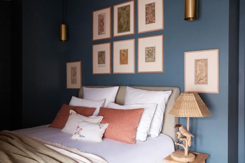 Schlafzimmer mit blauen Wänden und einem Bett mit Kissen in der Unterkunft Maisons 322 - L'Insolite in Le Bois-Plage-en-Ré