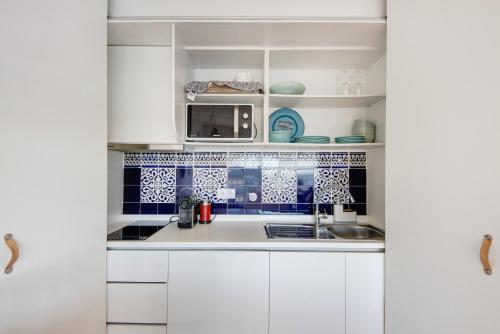 a kitchen with white cabinets and blue tiles at Apartamento T1 - Salina Ria in Aveiro