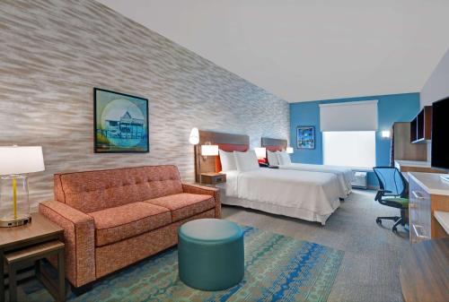フォートマイヤーズにあるHome2 Suites by Hilton Fort Myers Colonial Blvdのベッドとソファ付きのホテルルーム