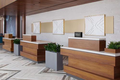 a lobby with wooden reception desks and potted plants at Hilton Garden Inn Camden Waterfront Philadelphia in Camden