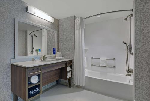 a bathroom with a sink and a tub and a mirror at Home2 Suites By Hilton Largo, Fl in Largo