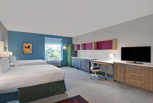 a hotel room with two beds and a desk with a television at Home2 Suites By Hilton Largo, Fl in Largo