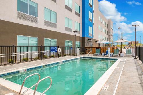 a swimming pool with chairs next to a building at Tru By Hilton Midland, Tx in Midland