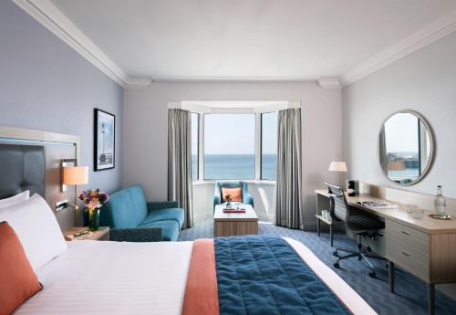 um quarto de hotel com uma cama grande e uma secretária. em Leonardo Royal Hotel Brighton Waterfront em Brighton & Hove