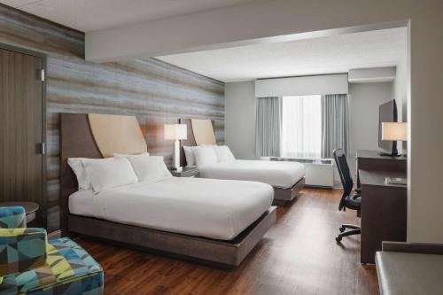 a hotel room with two beds and a desk at Hotel Trilogy Albany Airport, Tapestry Collection by Hilton in Latham