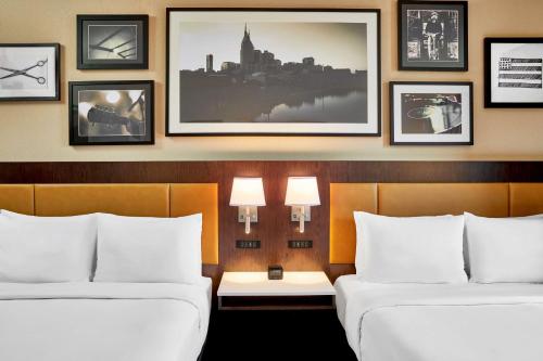 two beds in a hotel room with pictures on the wall at Embassy Suites by Hilton Nashville Downtown in Nashville