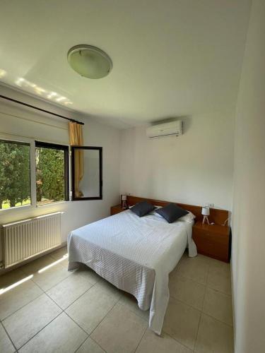 1 dormitorio con cama blanca y ventana en apartament la cova en Peralada
