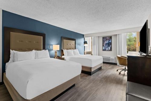 um quarto de hotel com duas camas e uma secretária em DoubleTree by Hilton Raleigh Midtown, NC em Raleigh