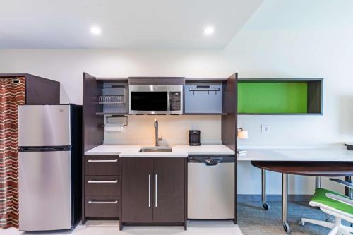 a kitchen with a refrigerator and a table and chairs at Home2 Suites By Hilton Midland East, Tx in Midland