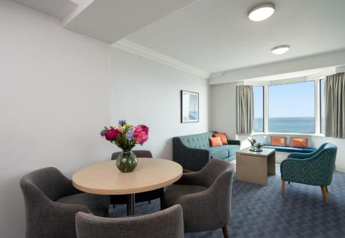 a living room with a table and chairs and a couch at Leonardo Royal Hotel Brighton Waterfront in Brighton & Hove