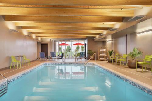 a hotel pool with chairs and tables and umbrellas at Home2 Suites By Hilton Martinsburg, Wv in Martinsburg