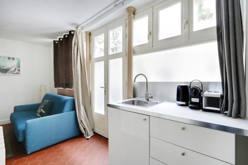 une cuisine avec un évier et une chaise bleue dans l'établissement Pick A Flat's Apartment in Montorgueil - Rue Léopold Bellan, à Paris