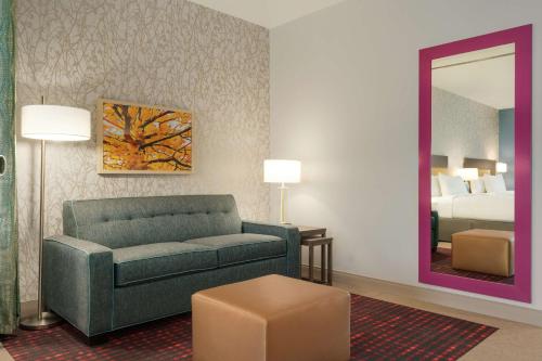 a living room with a couch and a bed and a mirror at Home2 Suites By Hilton Martinsburg, Wv in Martinsburg