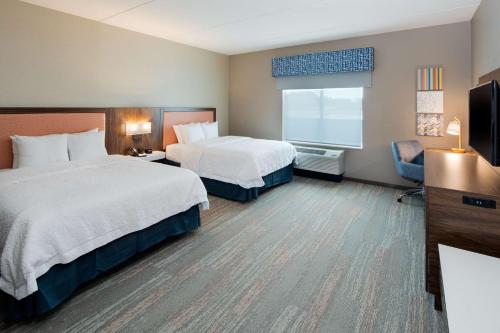 a hotel room with two beds and a television at Hampton Inn Smithfield Selma, NC in Smithfield