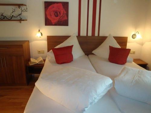 a large white bed with red pillows on it at Apart Austria in Nauders