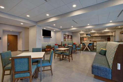 a waiting room with tables and chairs and a tv at Hampton Inn Brockville, On in Brockville
