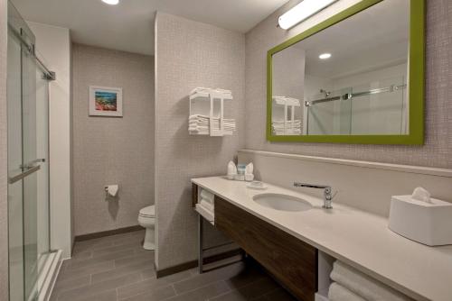 W łazience znajduje się umywalka, lustro i toaleta. w obiekcie Hampton Inn Brockville, On w mieście Brockville