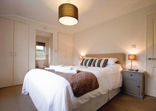 um quarto com uma grande cama branca e um candeeiro em Caddys Corner Lodges em Porkellis
