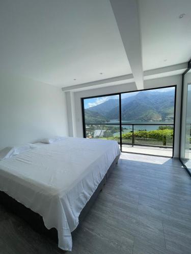 ein weißes Schlafzimmer mit einem Bett und einem großen Fenster in der Unterkunft Finca Lago Calima in Madroñal