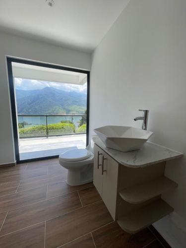 ein Badezimmer mit einem Waschbecken und einem WC mit einem großen Fenster in der Unterkunft Finca Lago Calima in Madroñal