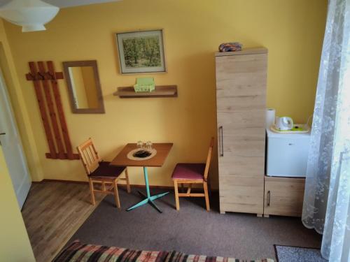 ピブニチュナ・ズドルイにあるWILLA "SZCZĘSNA"のテーブルと椅子、冷蔵庫が備わる小さな客室です。