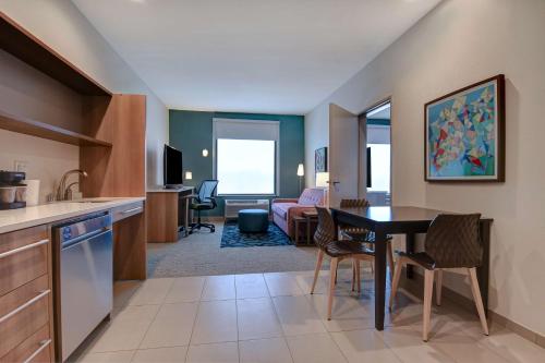 a kitchen and dining room with a table and a living room at Home2 Suites by Hilton North Plano Hwy 75 in Plano