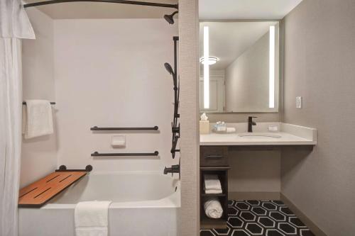 a bathroom with a tub and a sink and a mirror at Homewood Suites by Hilton Tuscaloosa Downtown- Near Univ of Alabama in Tuscaloosa