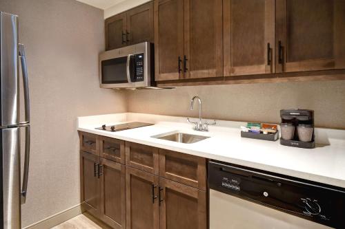 a kitchen with a sink and a microwave at Homewood Suites by Hilton Tuscaloosa Downtown- Near Univ of Alabama in Tuscaloosa