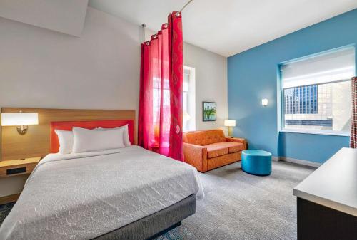 a bedroom with a bed and a chair and a window at Home2 Suites by Hilton Minneapolis Downtown in Minneapolis