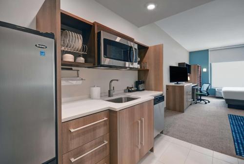 a small kitchen with a sink and a refrigerator at Home2 Suites By Hilton Raleigh North I-540 in Raleigh