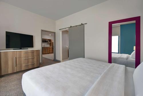 a bedroom with a bed and a flat screen tv at Home2 Suites By Hilton Raleigh North I-540 in Raleigh