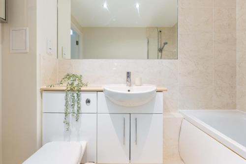uma casa de banho branca com um lavatório e um espelho em The Wimbledon Collection em Londres