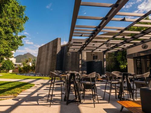 un patio avec des tables et des chaises sous une pergola dans l'établissement MS Milenium Monterrey Curio Collection by Hilton, à Monterrey