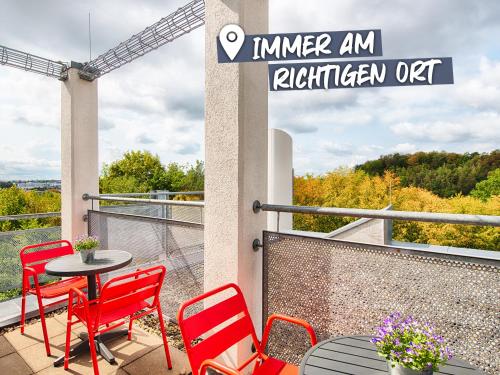 um pátio com cadeiras vermelhas e uma mesa na varanda em ACHAT Hotel Stuttgart Airport Messe em Stuttgart