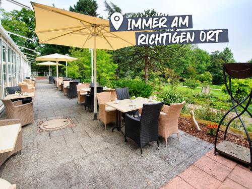 バート・デュルクハイムにあるACHAT Hotel Bad Dürkheimのテーブルと椅子、傘が備わるレストラン