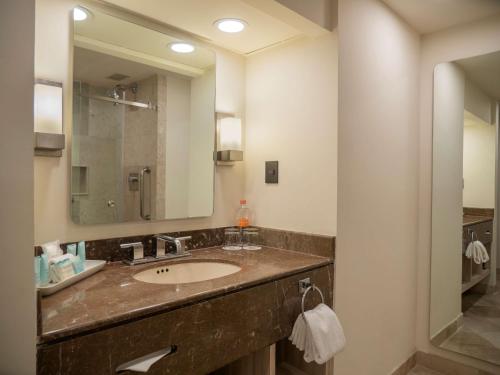 a bathroom with a sink and a mirror at MS Milenium Monterrey Curio Collection by Hilton in Monterrey