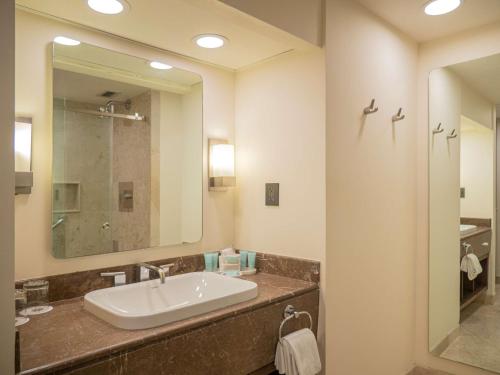 a bathroom with a sink and a mirror at MS Milenium Monterrey Curio Collection by Hilton in Monterrey